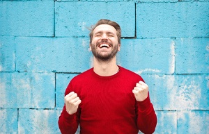 man in red sweater standing in front of blue brick wall