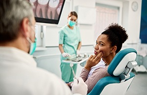 Woman with hand on cheek due to dental pain in dental office