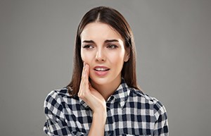 Woman in plaid with hand on cheek due to dental pain