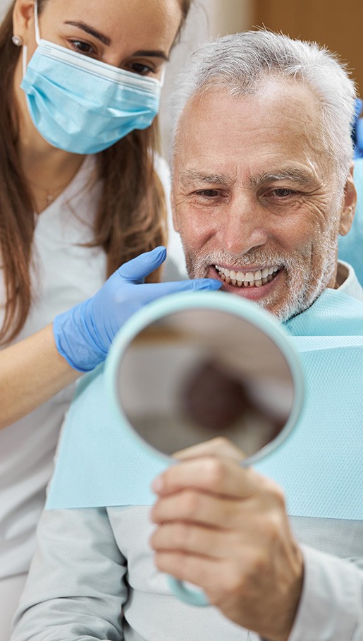 Man and dentist admiring his teeth in handheld mirror