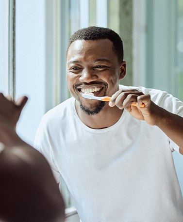 Man smiling while brushing his teeth