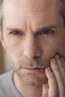 Man in pain putting his hand on the left side of his face