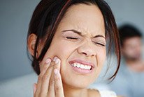 Close-up of woman rubbing jaw in pain