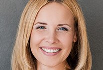 Blonde woman smiling in front of grey background