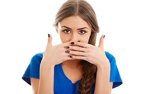Woman in blue shirt covering her mouth