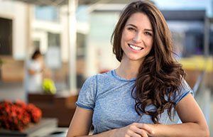 Woman in blue shirt standing outside and smiling