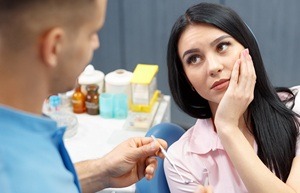 woman holding her cheek in pain