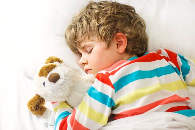 Boy sleeping in striped shirt with stuffed-animal