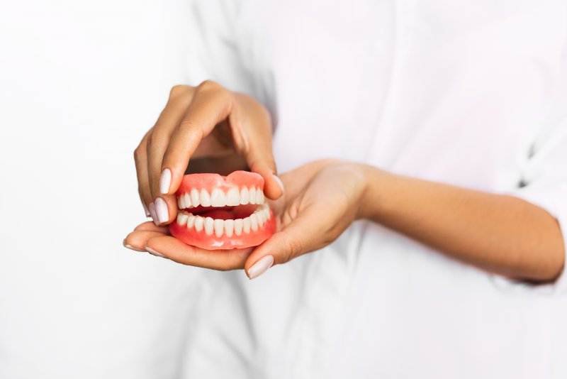 Close up of person holding upper and lower dentures
