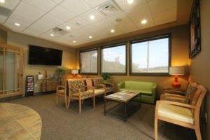 About Us: A welcoming waiting room with comfortable couches and a television for entertainment.