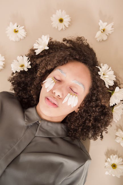 A woman laying on a bed with daisies on her face.