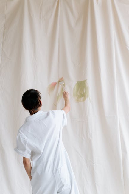 A woman is painting on a white curtain.